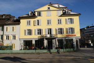 ein großes gelbes Gebäude in einer Stadtstraße in der Unterkunft Kränzlin Hotel in St. Gallen