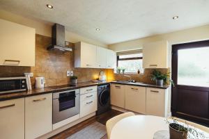a large kitchen with white cabinets and a table at Birchwood Cottage with hot tub in Valley