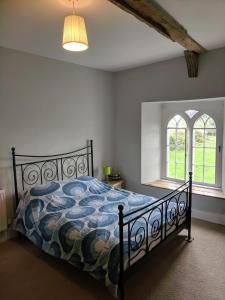 a bedroom with a bed with a blue comforter and two windows at Large Manor House near Bath in Trowbridge +7 photos
