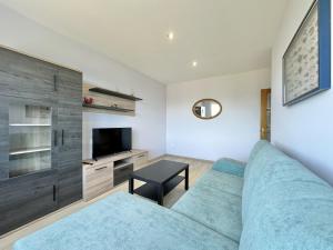 Una sala de estar con un sofá azul y un televisor en Front Beach I, en Sada 13 fotos más