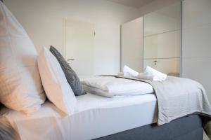 a bedroom with a white bed with pillows at HANNIBAL - Design Apartment Lavendel 4, VW Nähe, Parkplatz, Küche, HighSpeed-WLAN, Fitness, Solarium in Wolfsburg