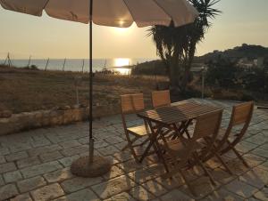 a table and chairs with an umbrella and the ocean at Villa La Falesia in Realmonte +25 photos