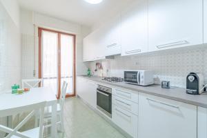 a white kitchen with white cabinets and a microwave at Mare e Monti a due Passi dalla Spiaggia! Ligurian Vacation Apartment in Chiavari