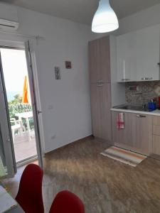 a kitchen with red chairs and an open door at Il Faro in Scalea +9 photos