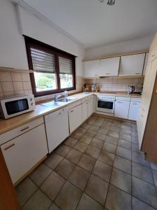 Eine Küche mit weißen Schränken, Spüle und Mikrowelle in der Unterkunft Wohnung Widdern in Widdern
