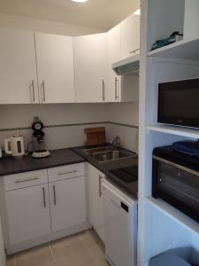 kuchnia z białymi szafkami, zlewem i kuchenką mikrofalową w obiekcie sweet-home w mieście Seignosse