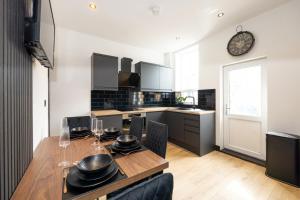 a kitchen with a wooden table with chairs and a clock at Midnight Manor-High Speed Wi-Fi-Cinema Room-Sleeps6 in Leigh +19 photos