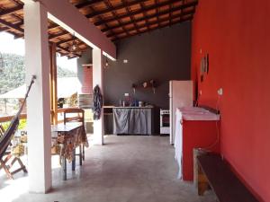 a kitchen with a red wall and a table with chairs at Suítes Doce Lar in Paraty