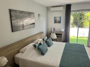 a bedroom with a bed with blue pillows at Hotel La Voile in Bormes-les-Mimosas