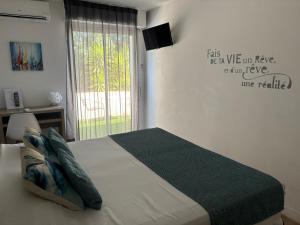 a bedroom with a large bed with a window at Hotel La Voile in Bormes-les-Mimosas