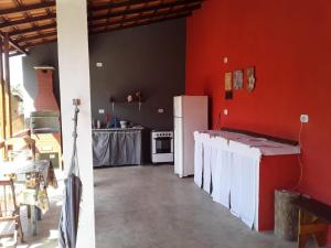 a kitchen with red walls and a white refrigerator at Suítes Doce Lar in Paraty +22 photos
