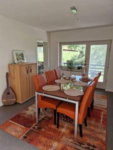 a dining room table with orange chairs and a kitchen at Ferienwohnung Grüne Auszeit in Nideggen +28 photos