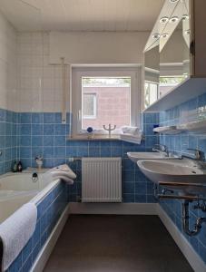 a blue tiled bathroom with a tub and a sink at Ferienwohnung Grüne Auszeit in Nideggen
