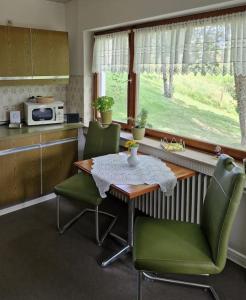 a kitchen with a table and two green chairs at Ferienwohnung Grüne Auszeit in Nideggen