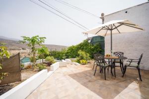 a patio with a table and chairs and an umbrella at Casa Rural da Eva in Santa Cruz de Tenerife