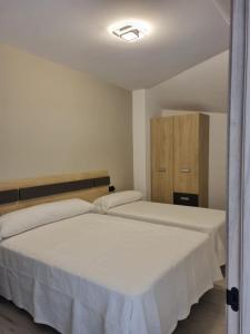 Un dormitorio con dos camas con sábanas blancas. en Loira IV, en Marín