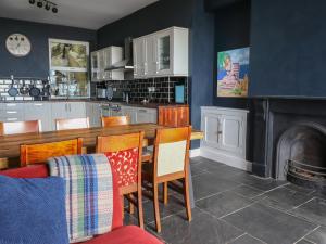 a kitchen with a table and chairs and a fireplace at Tonnau Yr Oleu or Waves of Light in Barmouth