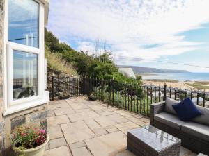 a patio with a couch and a view of the ocean at Tonnau Yr Oleu or Waves of Light in Barmouth