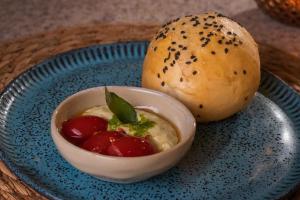 a blue plate with a bowl of soup and a roll at JANGA HOTEL BOUTIQUE in Maragogi