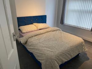 a bed with a blue headboard in a bedroom at Marvellous Room 1 in Stoke on Trent