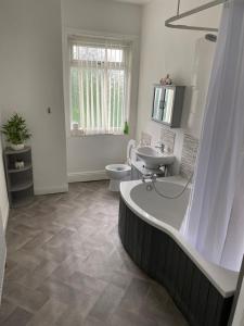 a bathroom with a tub and a toilet and a sink at Marvellous Room 1 in Stoke on Trent