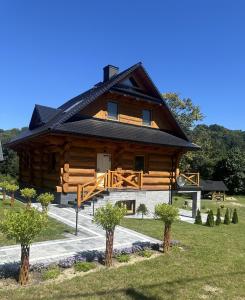 a large wooden house with a gambrel roof at Domki nad potokiem in Wetlina