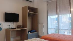 Un dormitorio con una cama y un televisor y una ventana. en Vince & Rita's home, en Sestri Levante