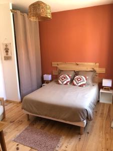 a bedroom with a bed with an orange wall at Charmante petite maison proximité Vichy centre in Vichy