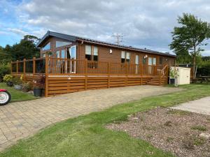 una grande casa in legno con un ampio ponte di Edinburgh Lodge-Sleeps 6-Pet Friendly-Beach&Views a Prestonpans