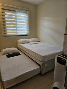 two twin beds in a room with a window at Joenice Lipa Staycation in Lipa
