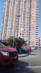 a red car parked in a parking lot in front of a large building at Icono central frente mall plaza 2 dormitorios in Antofagasta