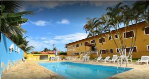 a resort with a swimming pool and a yellow building at Hotel Xapuri in Peruíbe
