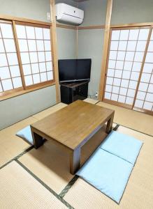 Nomuro伊根の宿 汐風 Shiokaze的带木桌的客房,位于带窗户的房间内