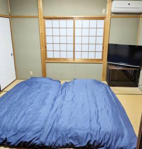 Nomuro伊根の宿 汐風 Shiokaze的一张大蓝色的床,位于一个配有电视的房间