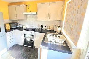 a kitchen with white cabinets and a stove top oven at Cozy 3-Bed House Near Willen Lake with Garden in Milton Keynes +8 photos
