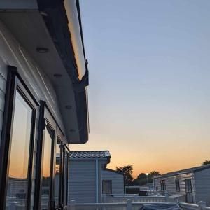 a building with windows and a sunset in the background at Isabel's Retreat in Mudeford