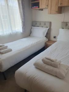 two beds in a room with towels on them at Isabel's Retreat in Mudeford
