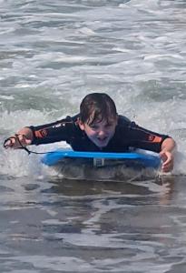 un joven tirado en una tabla de surf en el agua en 8 The Coombe, en Kilkhampton