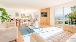 a living room with couches and a dining room with a table at Villa Panoramique - Lac du Bourget in Bourdeau