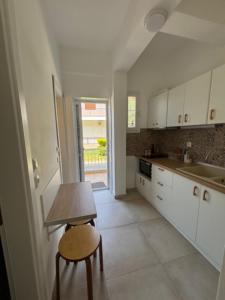 a kitchen with white cabinets and a table and a chair at Anna -House Maria Manolaki, 2-Βedrm Apartment in Vourvourou