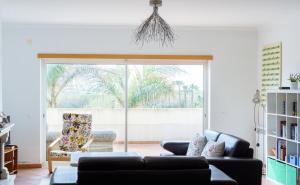 a living room with a couch and a sliding glass door at T3 terraço e piscina Praia del Rey Óbidos C14 in Amoreira