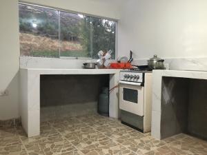Una cocina con estufa, fregadero y ventana. en Casa de montaña - Fundo Vilcar, en San Salvador