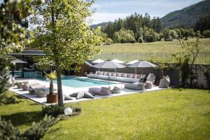 a pool with pillows and umbrellas in a yard at Hotel Petrus in Brunico