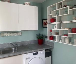 a kitchen with white cabinets and a washing machine at Cosy 1 bed apartment near Crantock beach in Crantock