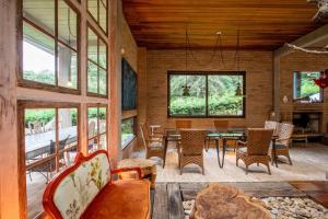 a living room with a table and chairs and windows at Design Home by The Lodges in Campos do Jordão