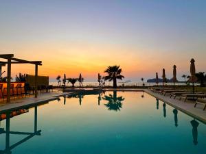 a swimming pool with a sunset in the background at Pachia Ammos Falasarna in Falasarna