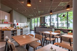 a restaurant with tables and chairs in a cafeteria at Novotel Suites München Parkstadt Schwabing in Munich