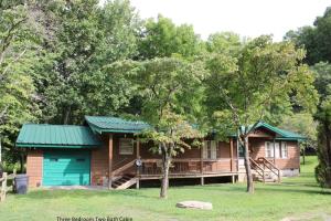 a cabin in the woods with a green roof at Two Rivers Lodge in Bryson City