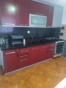 a kitchen with red cabinets and a sink at Λευκό σπίτι in Ksamil