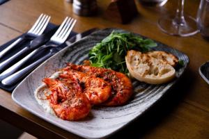 a plate of food with shrimp and greens on a table at The Kings Head Inn, Home of The Acle Steak in Acle